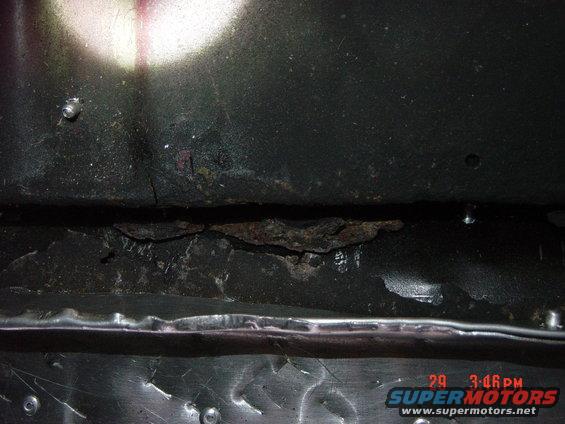 Close-up of a heavily rusted and damaged vehicle frame section