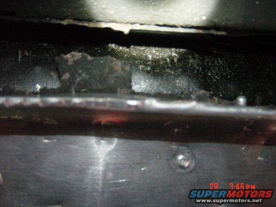 Close-up of the underside of a vehicle, showing rust and dirt. There's a timestamp in the corner