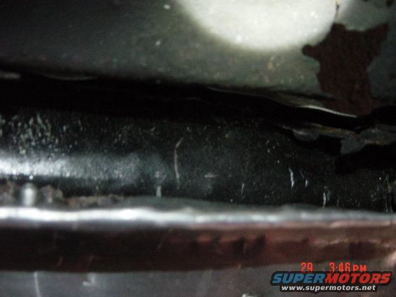 Underside view of a vehicle frame with some rust and dirt