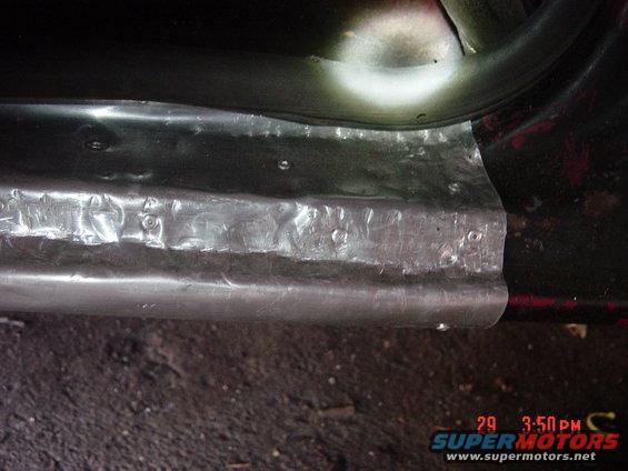 Close-up of a repaired rocker panel with visible rivets and metalwork