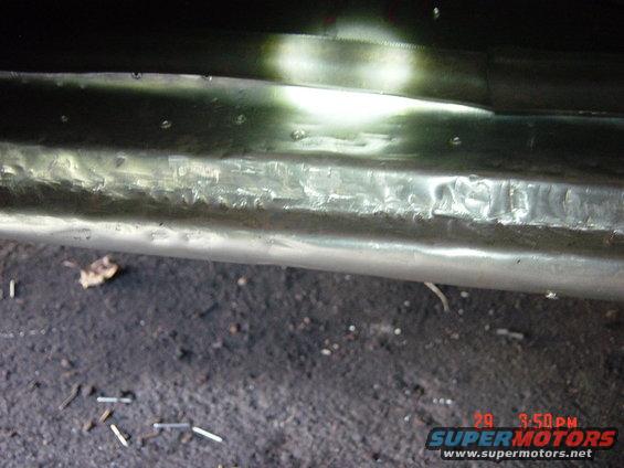 Close-up of a damaged metal panel with visible rivets and texture. Date stamp '20 3:50PM' and 'SUPERMOTORS.NET' watermark
