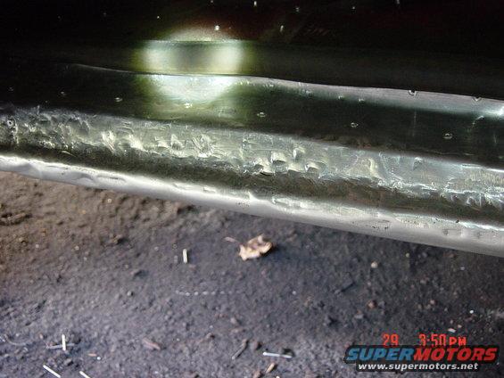Dented metal panel with rivets, close-up view. Supermotors.net watermark visible