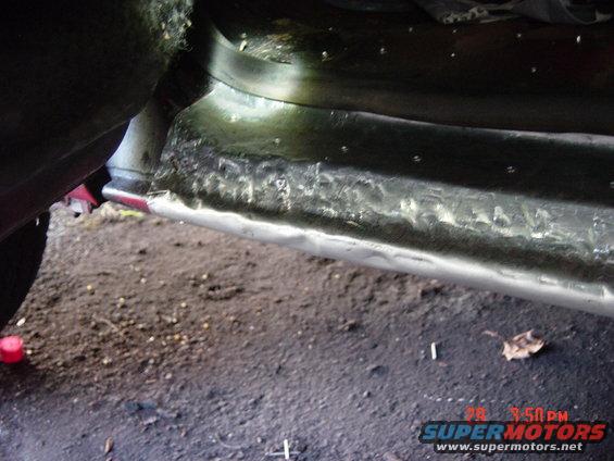Close-up of rusted metal on a vehicle's rocker panel, showing repair work