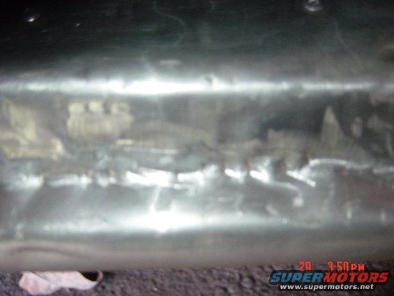 Close-up of a dented and scratched metal surface, possibly a car part