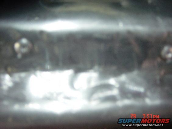 Close-up of a metal bar with visible screws, possibly part of a vehicle's undercarriage