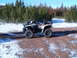 1994 Jeep Cherokee - An all-terrain vehicle sits on a dirt path surrounded by snow and pine trees under a clear blue sky.
