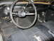 1964 Ford Ranchero - The interior of a classic car shows a worn steering wheel and cracked seat upholstery.