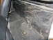 1964 Ford Ranchero - The interior of a vehicle shows a black vinyl panel with stitched pockets and dark carpeted floor.