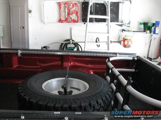 Truck bed with spare tire, ladder, and weed trimmer mounted on wall