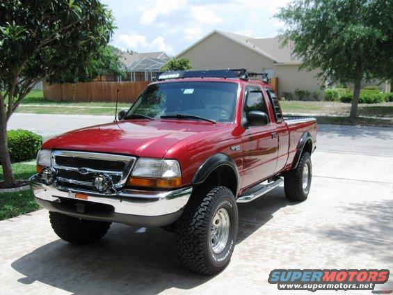 Red 1999 Ford Ranger pickup truck with roof rack and off-road tires