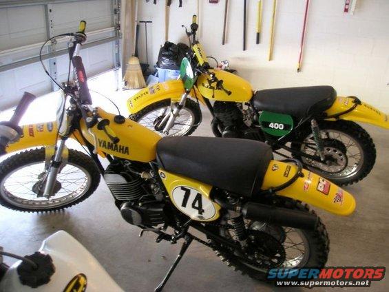 Two yellow Yamaha dirt bikes parked in a garage, one with number 74, the other with number 400