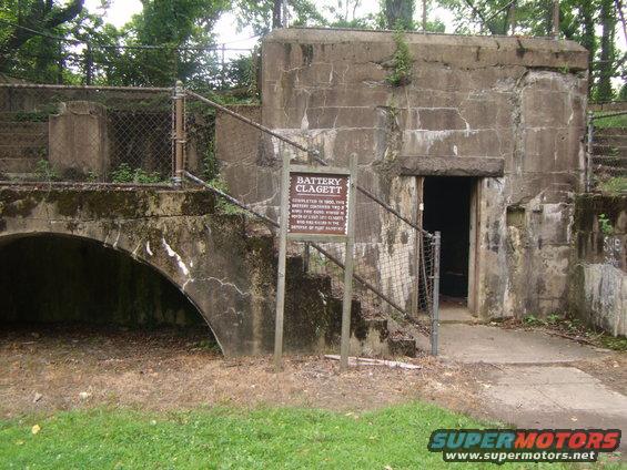 Concrete bunker structure with a sign reading 'Battery Clagett' and an arched opening