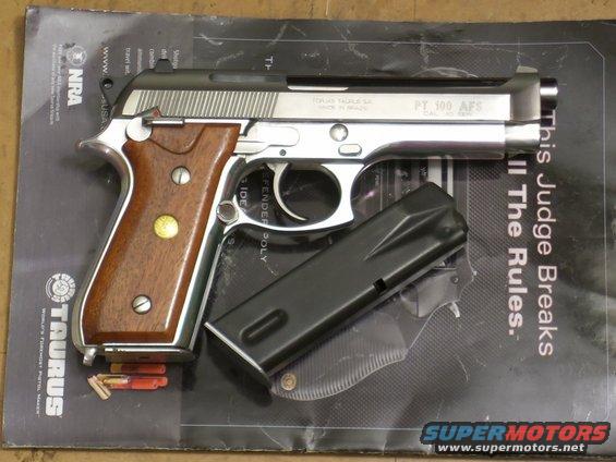 Taurus PT 100 AFS pistol, silver and black with wood grips, next to a black magazine and ammunition