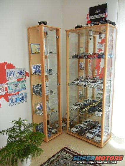 Model cars displayed in glass cabinets, with license plates on the wall