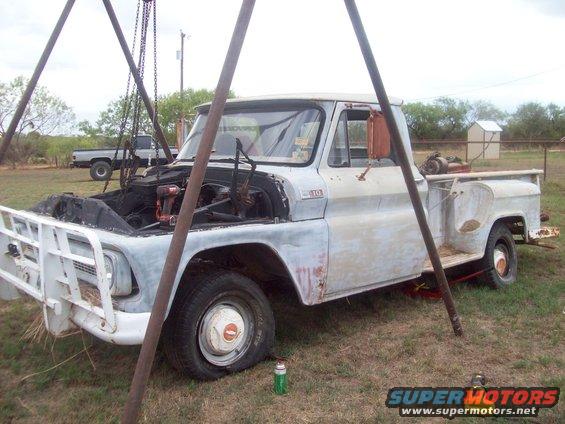 Old pickup truck with hood open, being worked on. Another truck is parked in the background