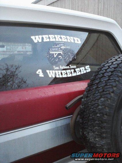 Rear side of a Ford Bronco with a spare tire mounted. Window has stickers saying 'WEEKEND 4 WHEELERS' and 'San Antonio, Texas'