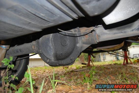 underneath view of a vehicle's rear axle assembly, with exhaust pipe and fuel tank visible