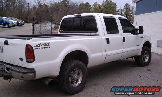 White 2002 Ford F-250 Super Duty pickup truck, 4x4 Off Road decal on bed, parked outdoors