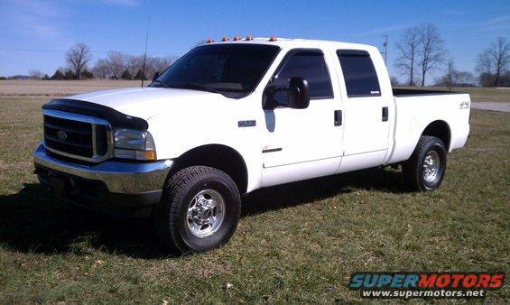 2002 Ford F-250 Super Duty pickup truck, white, four doors, parked on grass