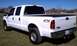 2002 Ford F-250 - A white Ford F-250 pickup truck is shown from the rear quarter angle, parked on a grassy area.