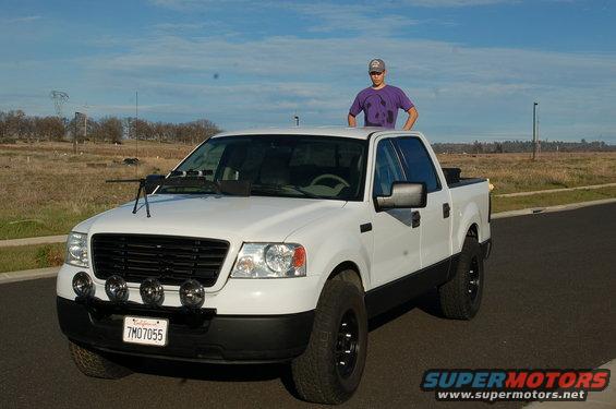 White pickup truck with a person standing on the roof. Has a gun mounted on the hood
