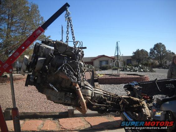 Engine and transmission assembly suspended by chains from a red engine hoist