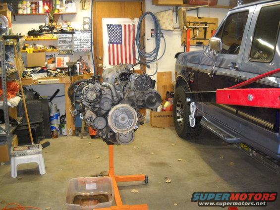 Engine on stand in garage next to a Ford truck