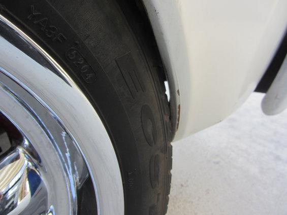 Close-up of tire and rusted wheel well