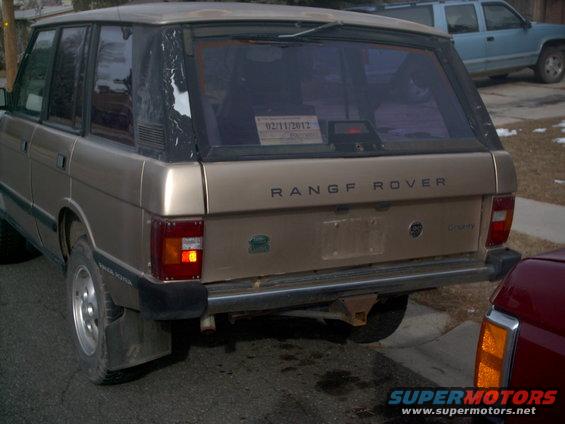 1991 Land Rover Range Rover rear view. Tan paint, black trim, tinted windows. License plate area is blank