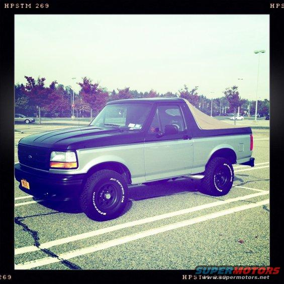 Two-tone gray and black 1992 Ford Bronco with a tan soft top parked in a lot