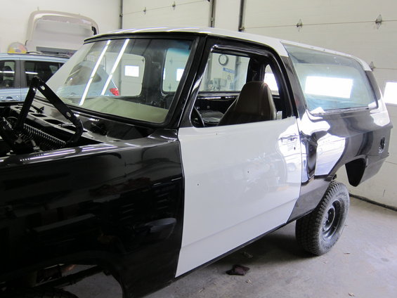 1987 Dodge Ramcharger in a garage, undergoing bodywork with primer and black paint