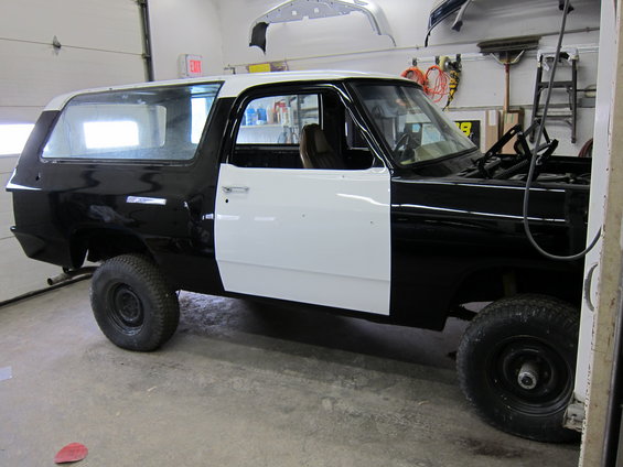 1987 Dodge Ramcharger in black and white primer, hood open, in a garage
