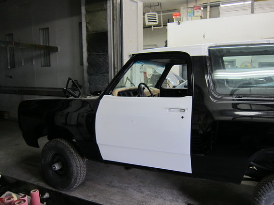 Black and white pickup truck, driver's side view, undergoing bodywork