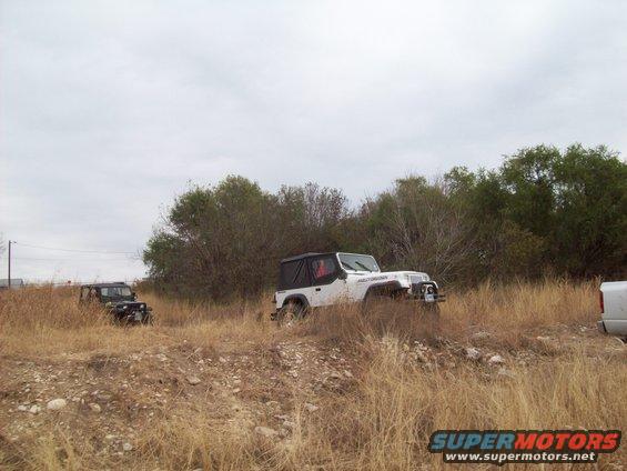 white Jeep Wrangler and black Jeep Wrangler in tall dry grass, cloudy day