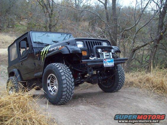 Black Jeep Wrangler with Monster Energy decals on a dirt trail