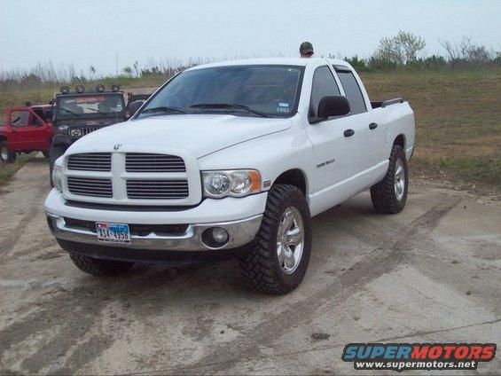 White Dodge Ram pickup truck parked on dirt, with a red Jeep and a black Jeep in the background