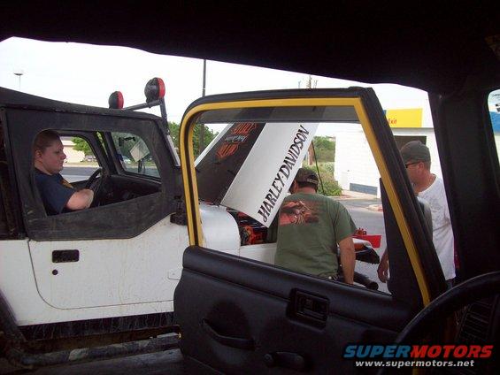 Two Jeep Wranglers with hoods open; one has a Harley Davidson decal on the hood