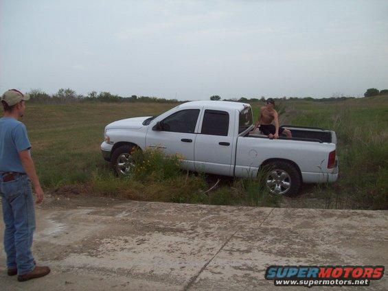 guy sitting in bed of white pickup truck parked in grassy field