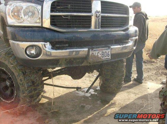 Dark blue pickup truck front end with chrome grille and bumper, lifted suspension, large tires, and a license plate reading OLC-806