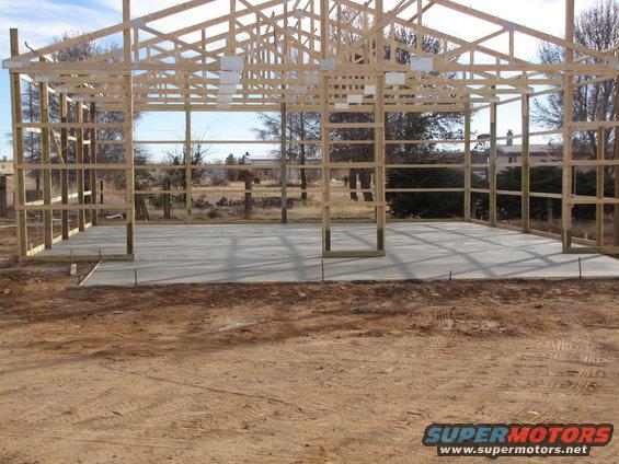 Wooden frame of a barn under construction with a concrete floor poured