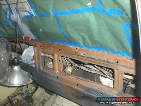 interior of vehicle with dashboard removed, wires exposed, and area taped off for painting