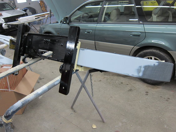 Black and gray bumper assembly on sawhorses, with a green SUV in the background