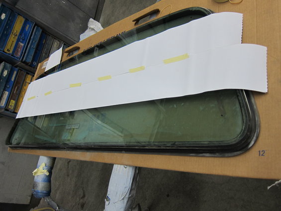 Car window with white paper taped over it, resting on cardboard