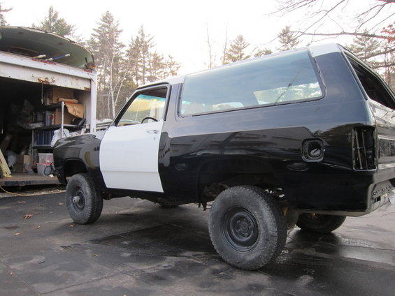 Dodge Ramcharger in black and white, undergoing restoration. Parked next to a trailer