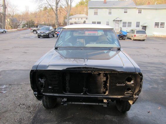 Front view of a black pickup truck with its grille removed. The vehicle appears to be undergoing some work