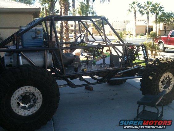 Custom buggy with roll cage, large tires, and cooler, parked on driveway