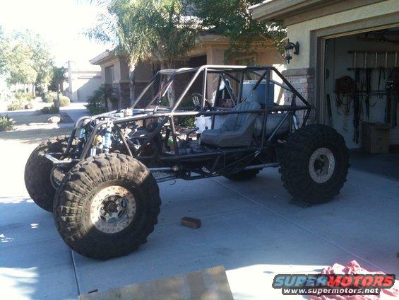 Custom buggy frame with large tires and a single seat, parked in a driveway