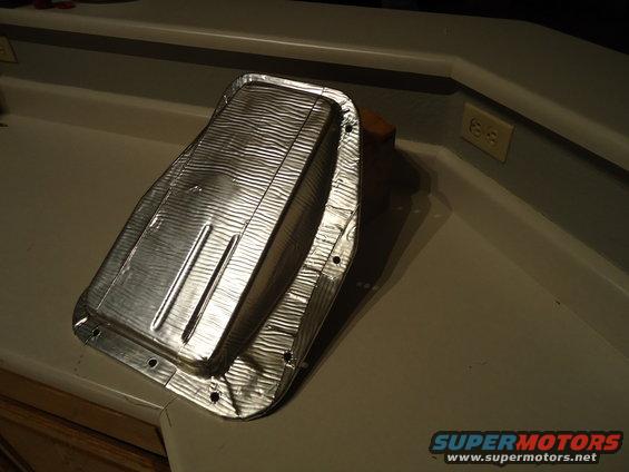 Metal heat shield with textured surface and bolt holes