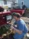 1987 Ford Ranger - Man works on the front end of a red 1987 Ford Ranger, with a truck bed and another vehicle in the background.
