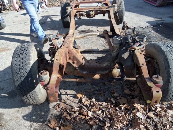 Rusted truck frame with front wheels and suspension components visible
